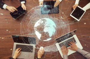 Decorative stock image demonstrating digital teamwork and global network using an image of digital information devices with an overlay of the earth.