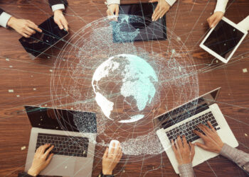 Decorative stock image demonstrating digital teamwork and global network using an image of digital information devices with an overlay of the earth.