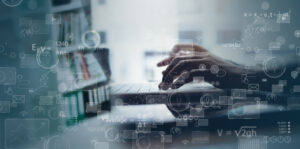 hands working on a laptop in front of a shelf full of books