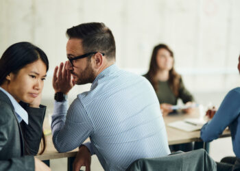 person whispering an aside to another person in a business setting