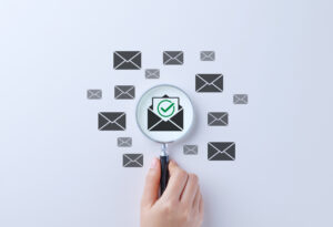 Decorative image: Email Verification and Filtering Concept. A magnifying glass focusing on a verified email icon with envelope symbols, secure email filtering, and validation. spam virus, phishing, fraud, scam mail,