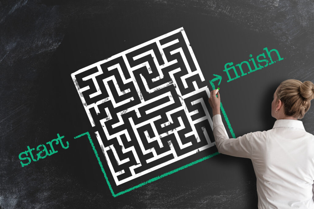 woman bypassing labyrinth by drawing line around it as a workaround on blackboard