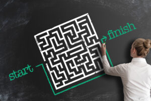 woman bypassing labyrinth by drawing line around it as a workaround on blackboard