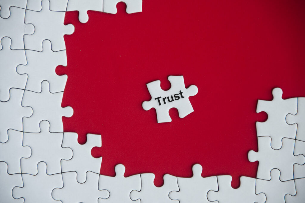 decorative image depicting the business concept of trust, with the word "Trust" on missing jigsaw puzzle