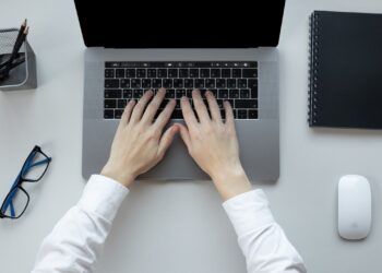 overhead view of hands placed on a laptop keyboard