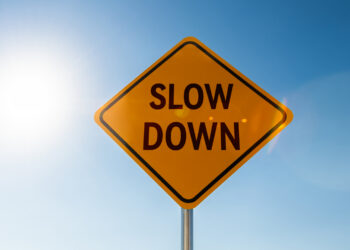 road sign reading "slow down" against a blue sky
