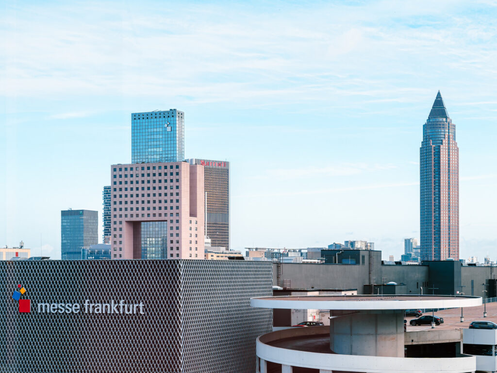 Skyline view of Messe Frankfurt with modern skyscrapers, including the iconic Messeturm, against a clear blue sky
