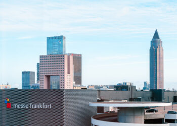 Skyline view of Messe Frankfurt with modern skyscrapers, including the iconic Messeturm, against a clear blue sky