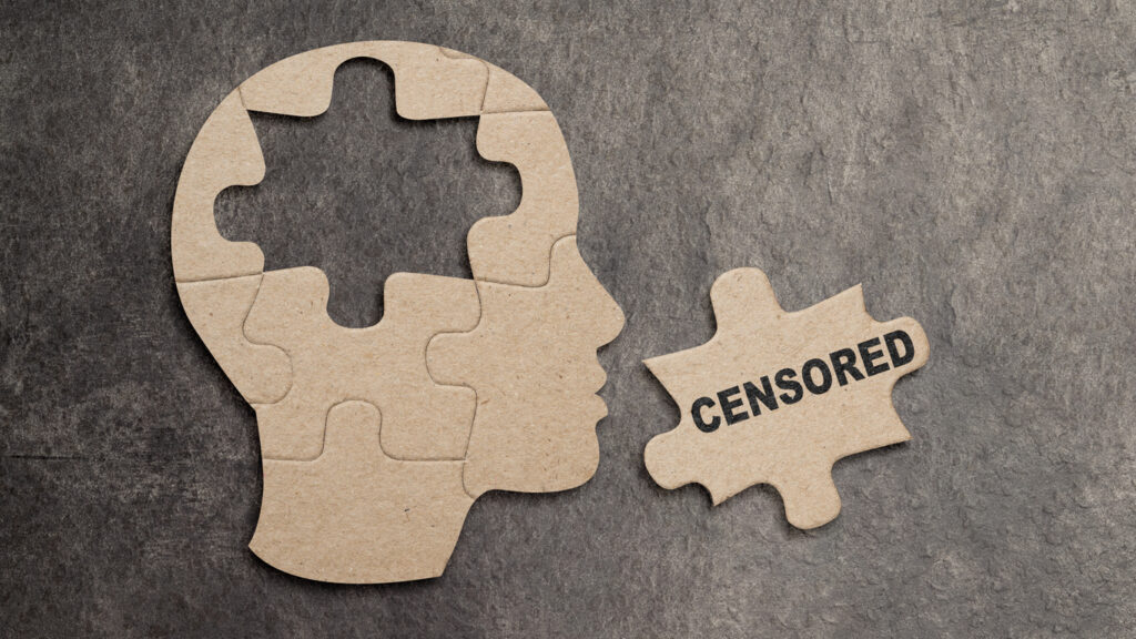 Conceptual image of a jigsaw puzzle in the shape of a human profile with a central piece removed and labeled CENSORED